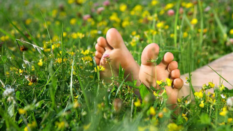 Nahaufnahme nackte Füße in Blumenwiese