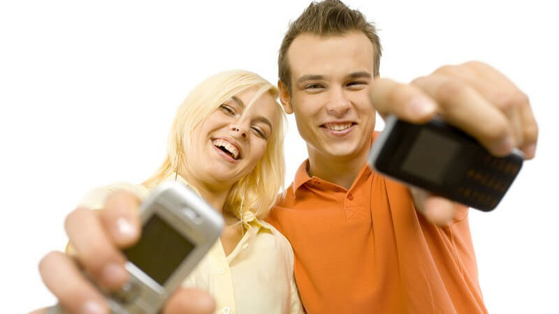 Junges lachendes Paar streckt Handy in Kamera