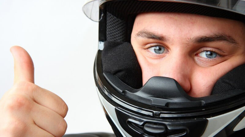 Motorradfahrer mit Helm zeigt Daumen nach oben