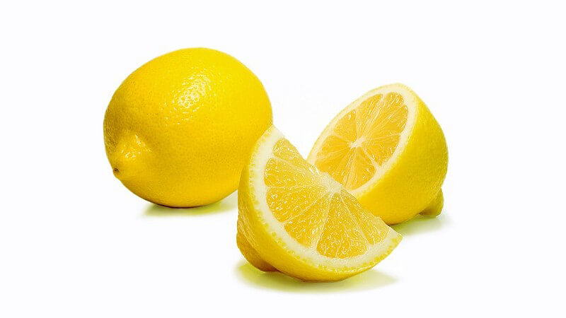 Frische Zitronen, teilweise aufgeschnitten, auf weißem Hintergrund