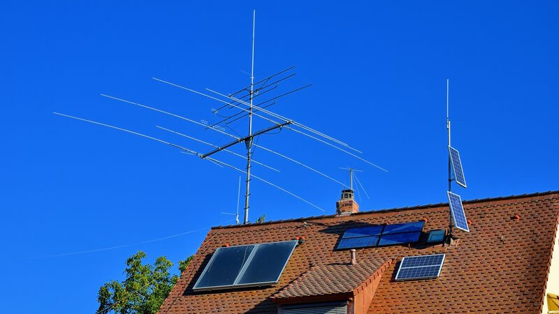 Dach eines Hauses mit Solaranlage und Amateurfunk-Antenne unter blauem Himmel