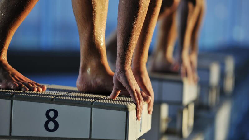 Schwimmwettkampf: Sportler kurz vor Absprung ins Wasser