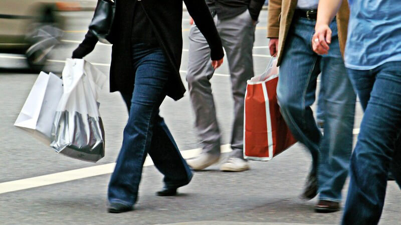 Unterkörper mehrerer Menschen auf Straße mit Einkaufstaschen