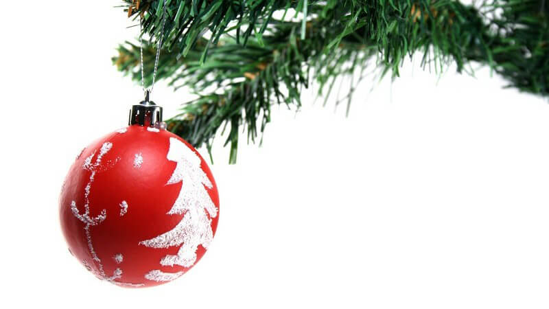 Rote Christbaumkugel an Weihnachtsbaum auf weißem Hintergrund