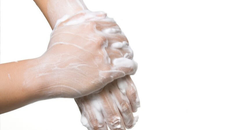 Eingeseifte Hände beim Händewaschen auf weißem Hintergrund