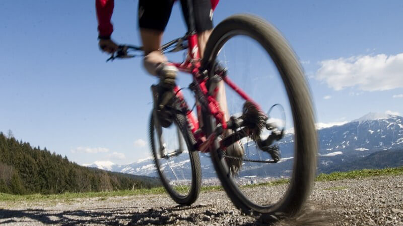 Mountainbike Fahrer unterwegs auf Radweg in Berglandschaft