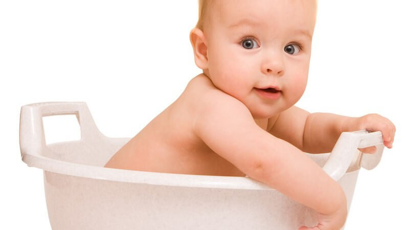 Baby sitzt in kleiner Badewanne, weißer Hintergrund