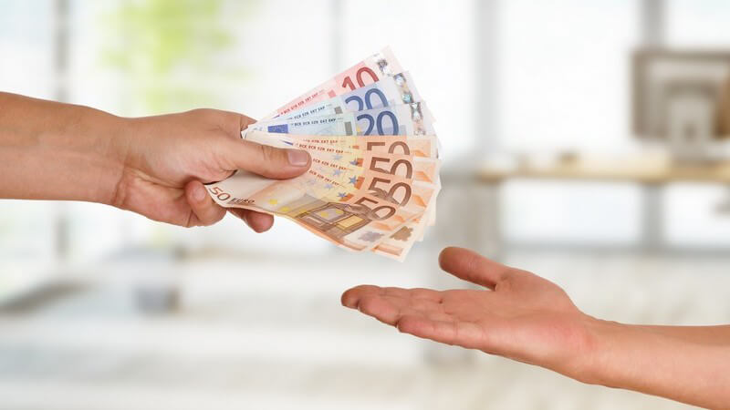 Person überreicht einer anderen handaufhaltenden Person 250 Euro Bargeld