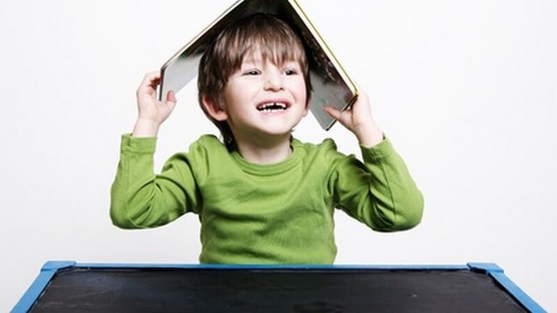 Kind mit Buch über dem Kopf
