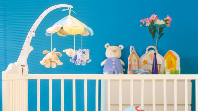 Blau angestrichenes Babyzimmer mit Babybett und Kuscheltieren