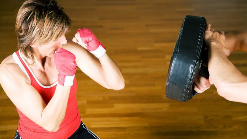 Frau im Sportoutift beim Boxen gegen ein Boxkissen