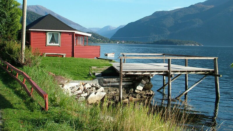 Rotes Häusschen und kleiner Bootssteg an einem norwegischen Fjord