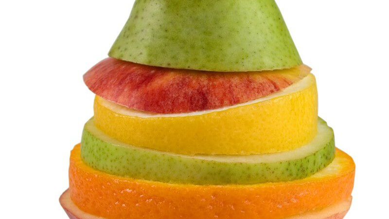 Gemischte, zusammengesetzte Frucht aus Fruchtscheiben von Birne, Apfel, Zitrone, Orange, vorne zwei Weintrauben
