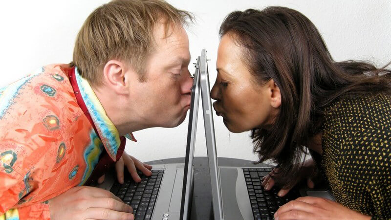 Internet-Liebe, Mann und Frau sitzen an Notebook, küssen Bildschirm, Webcam
