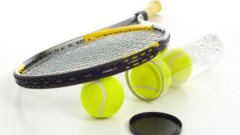 Gelb-schwarzer Tennisschläger liegt auf geöffneter Dose mit grünen Tennisbällen vor weißem Hintergrund