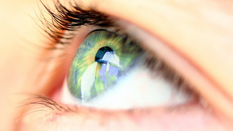 Nahaufnahme grünes Auge einer jungen Frau, Blick nach oben, Foto von Seite