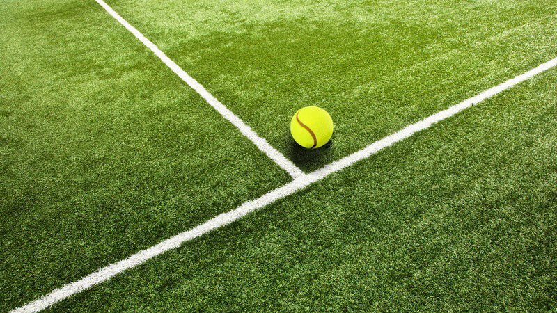 Ausschnitt Tennisfeld, Rasen mit Spielfeldmarkierung und Tennisball