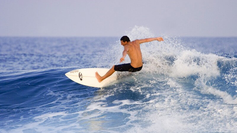 Dunkelhaariger Surfer auf Surbrett im Meer, Malediven