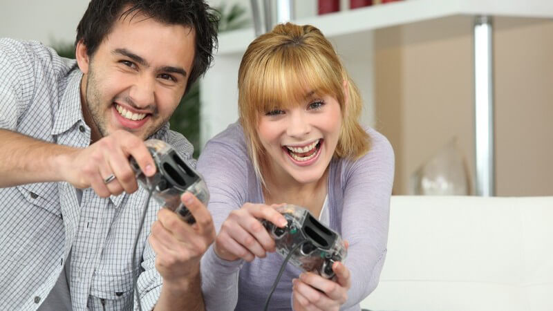 Junger Mann und Frau haben Spaß beim Videospiel, haben beide Controller in den Händen