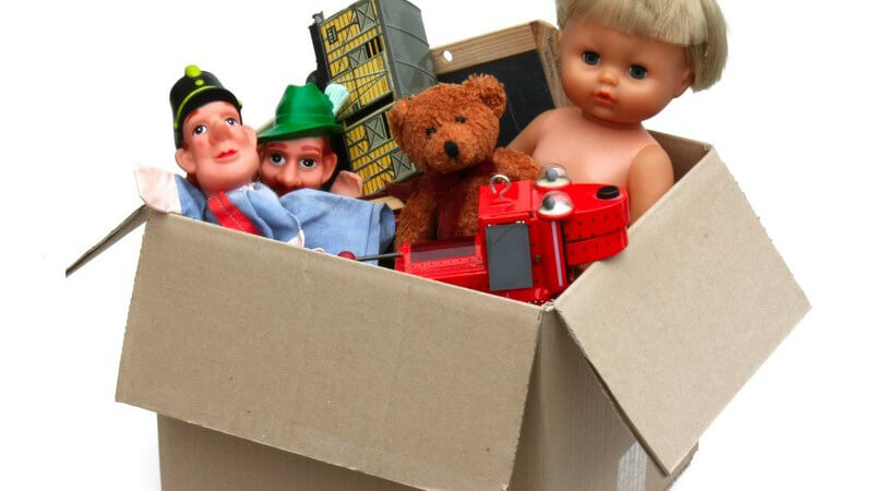 Karton mit verschiedenen Kinderspielzeugen und Puppen