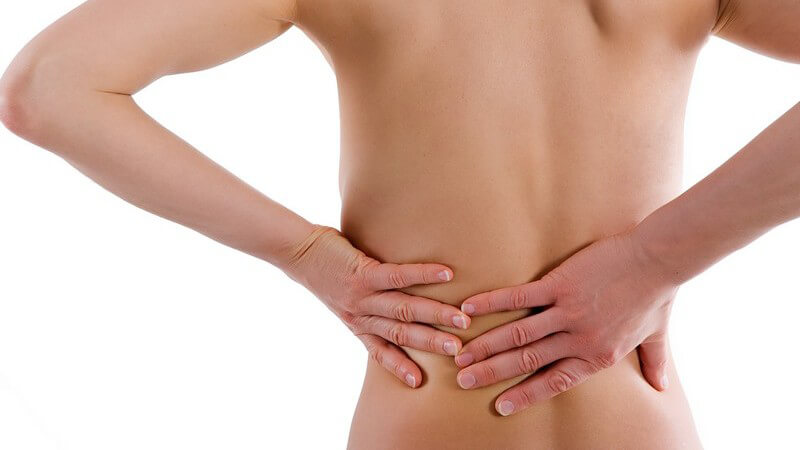 Symptome - Frau mit Rückenschmerzen fasst sich mit beiden Händen an den Rücken