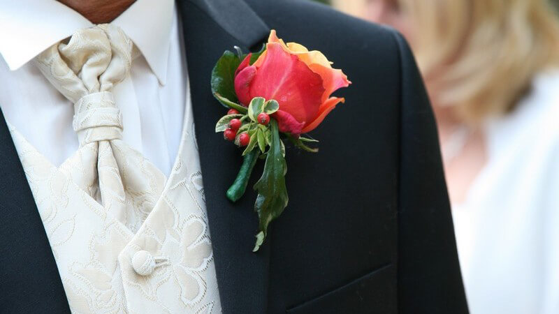 Rote Ansteckblume an dunklem Anzug eines Bräutigams