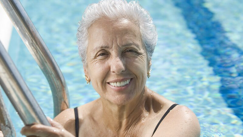 Ältere, lächelnde Frau im Schwimmbecken