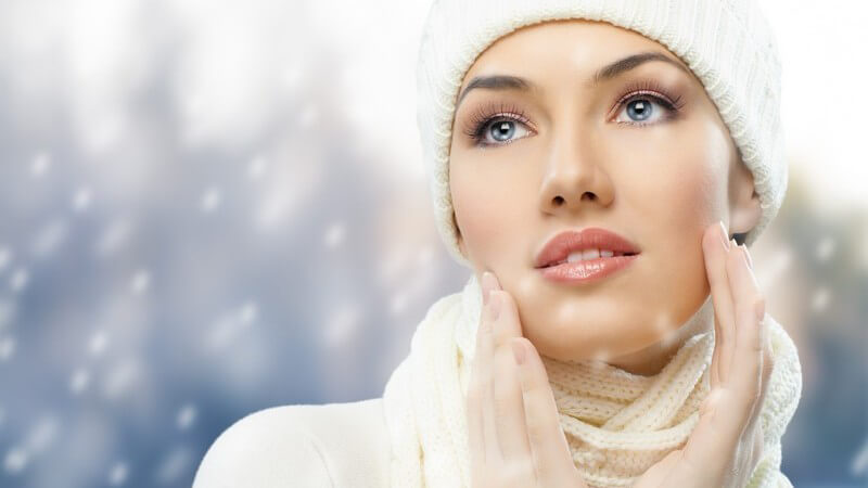Junge Frau mit Schal, Mütze und Strickpulli, Grafik mit Schneeflocken, Winter