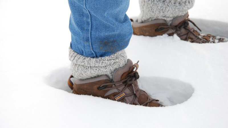Beine in Jeans, Winterschuhe im Schnee