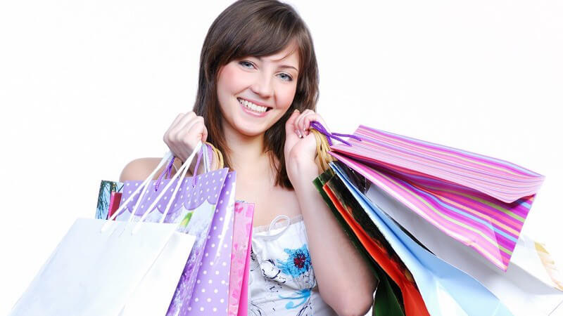 Junge glückliche Frau hält viele Einkaufstüten in den Händen