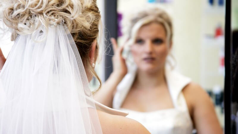 Braut vor Spiegel prüft ihre Frisur
