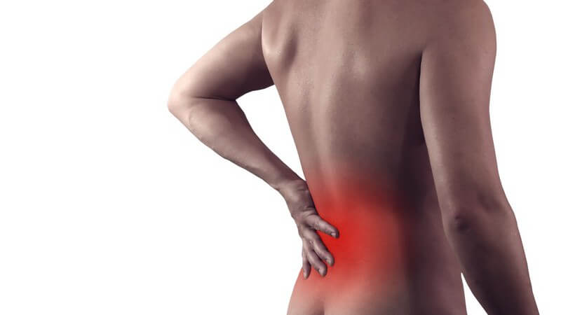 Rückenschmerzen - Nackter Mann fasst sich an den rot hervorgehobenen Rücken