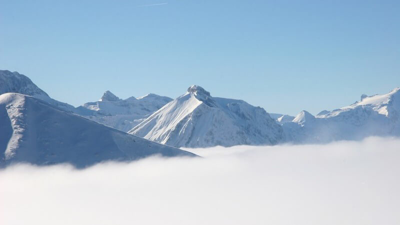 Berge in Alpen unter blauem Himmel, von Nebel umgeben