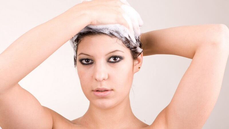 Haarwäsche - Junge Frau schäumt sich ihr Haar mit Shampoo ein