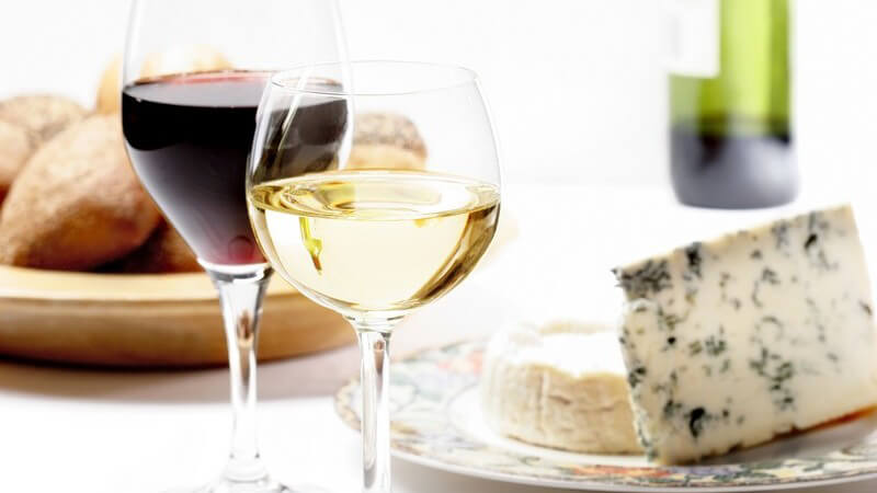 Französisches Essen mit Weißweinglas, Rotweinglas, Rotweinflasche, Brot und Gorgonzola oder Blauschimmelkäse