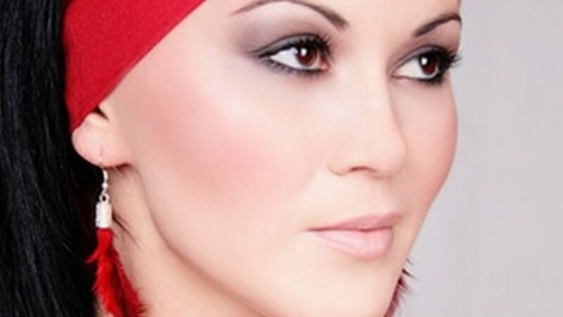 Dunkelhaarige Frau mit rotem Stirnband und roten Federohrringen